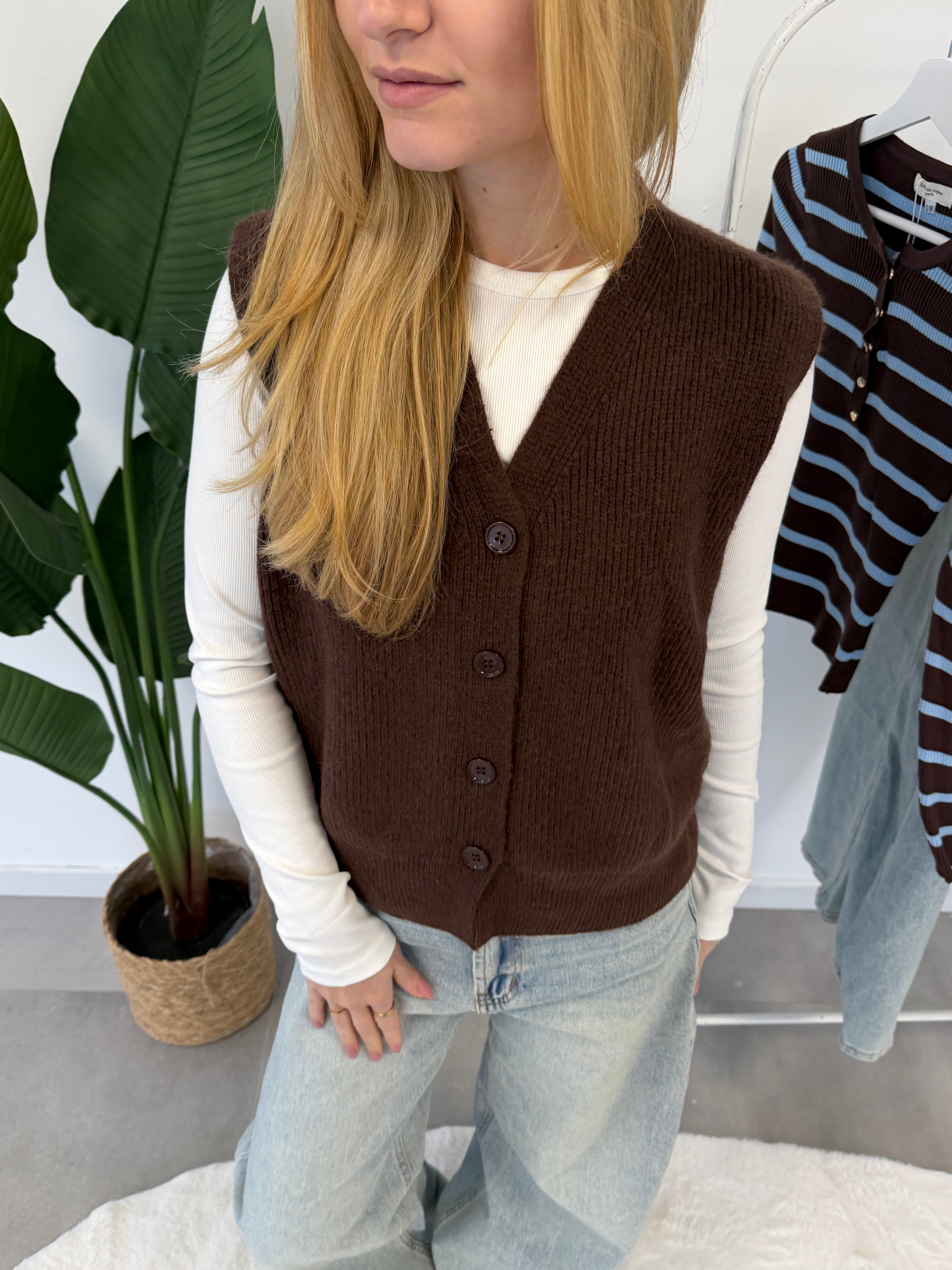 Lola gilet – bruin gebreid damesgilet met knoopjes aan de voorkant, gestyled met een witte longsleeve